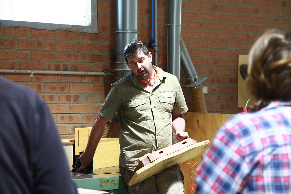 A master furniture maker discusses the use of the spindle moulder during a woodworking course.