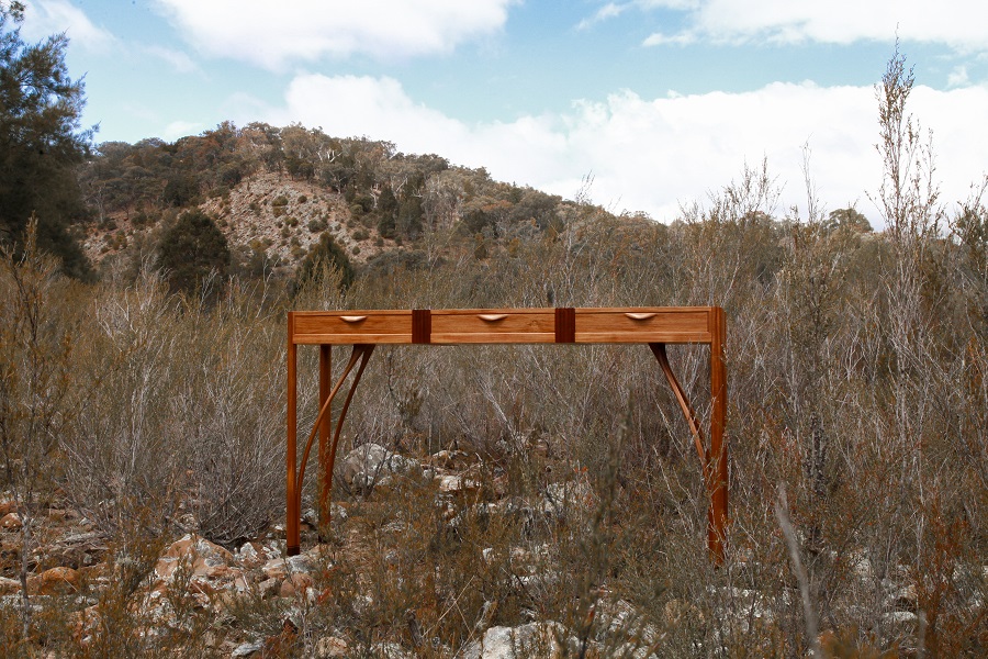 Handmade timber side table sitting in long grass on rock in the Australian landscape