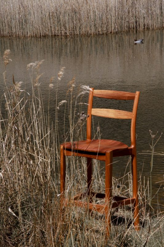 Handmade timber stool sitting in long grass next to the Molonglo river in the Australian landscape