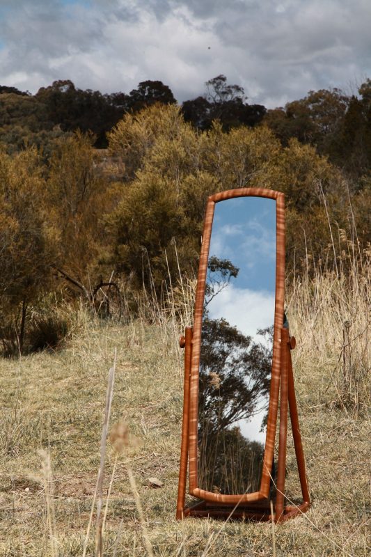 Handmade timber mirror sitting in long grass in the Australian landscape