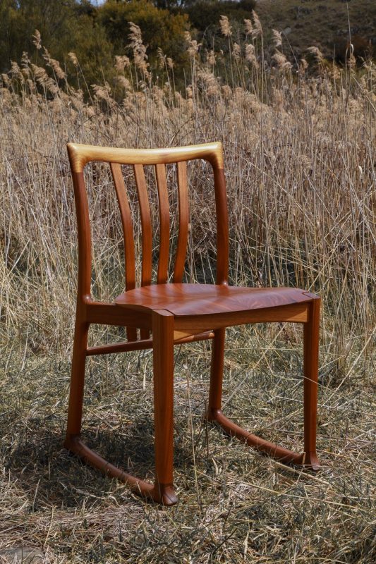 Handmade timber chair sitting in long grass in the Australian landscape