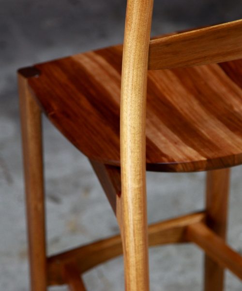 A high stool with a back rest designed for Australian houses and made from native timbers.
