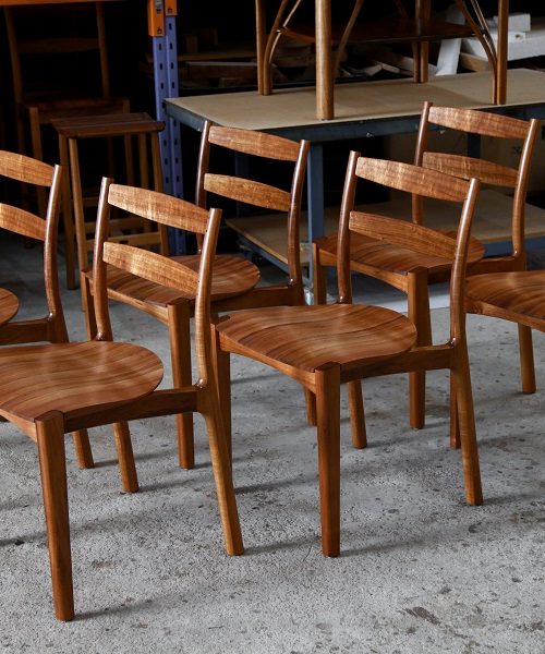 A set of Australian designed and made low back dining chairs in Tasmanian blackwood in a woodworking workshop.