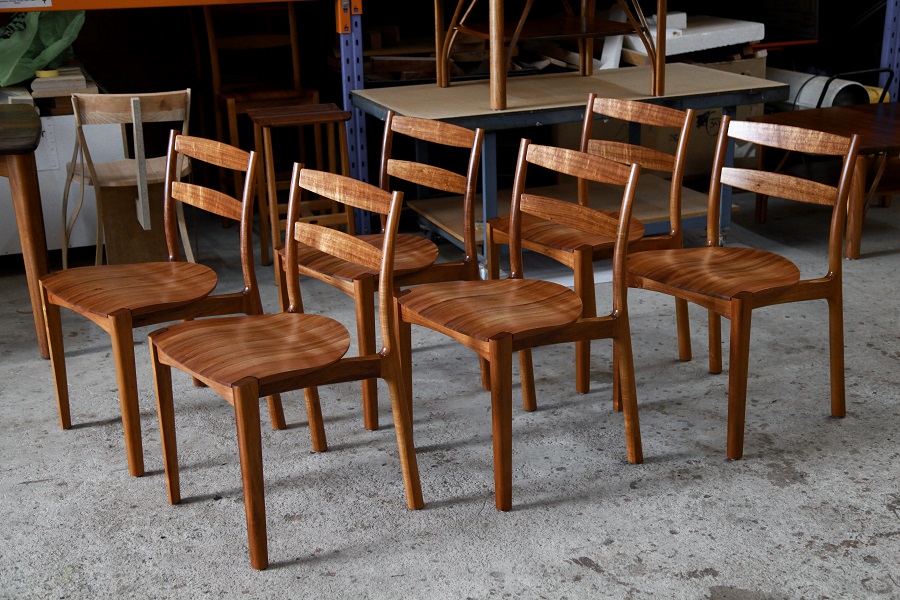 A set of Australian designed and made low back dining chairs in Tasmanian blackwood in a woodworking workshop.