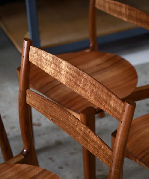 A set of Australian designed and made low back dining chairs in Tasmanian blackwood in a woodworking workshop.