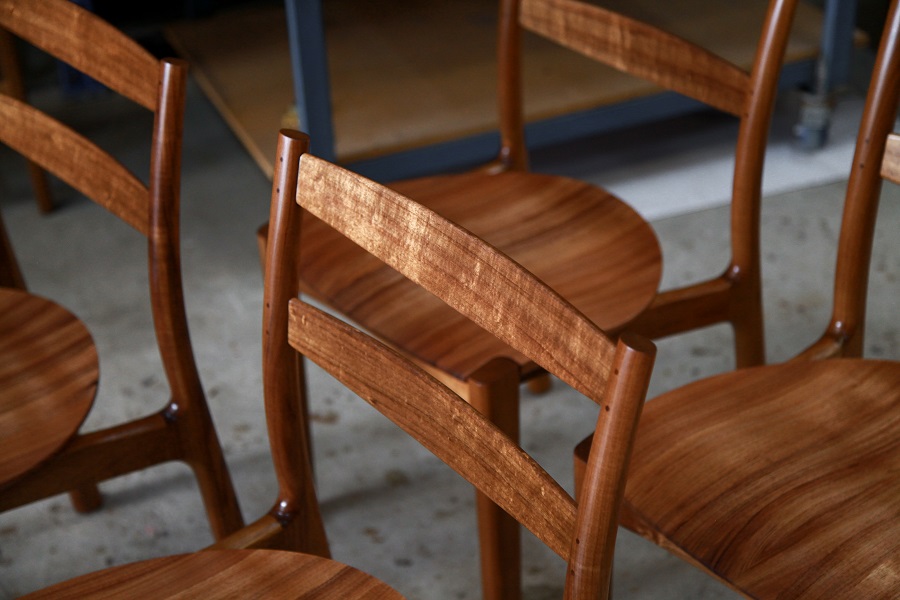 A set of Australian designed and made low back dining chairs in Tasmanian blackwood in a woodworking workshop.