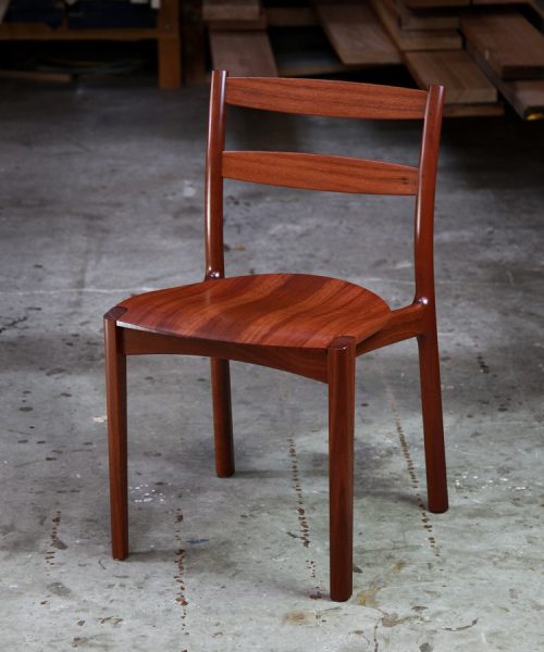 An Australian designed and made low back dining chair in jarrah in a woodworking workshop.