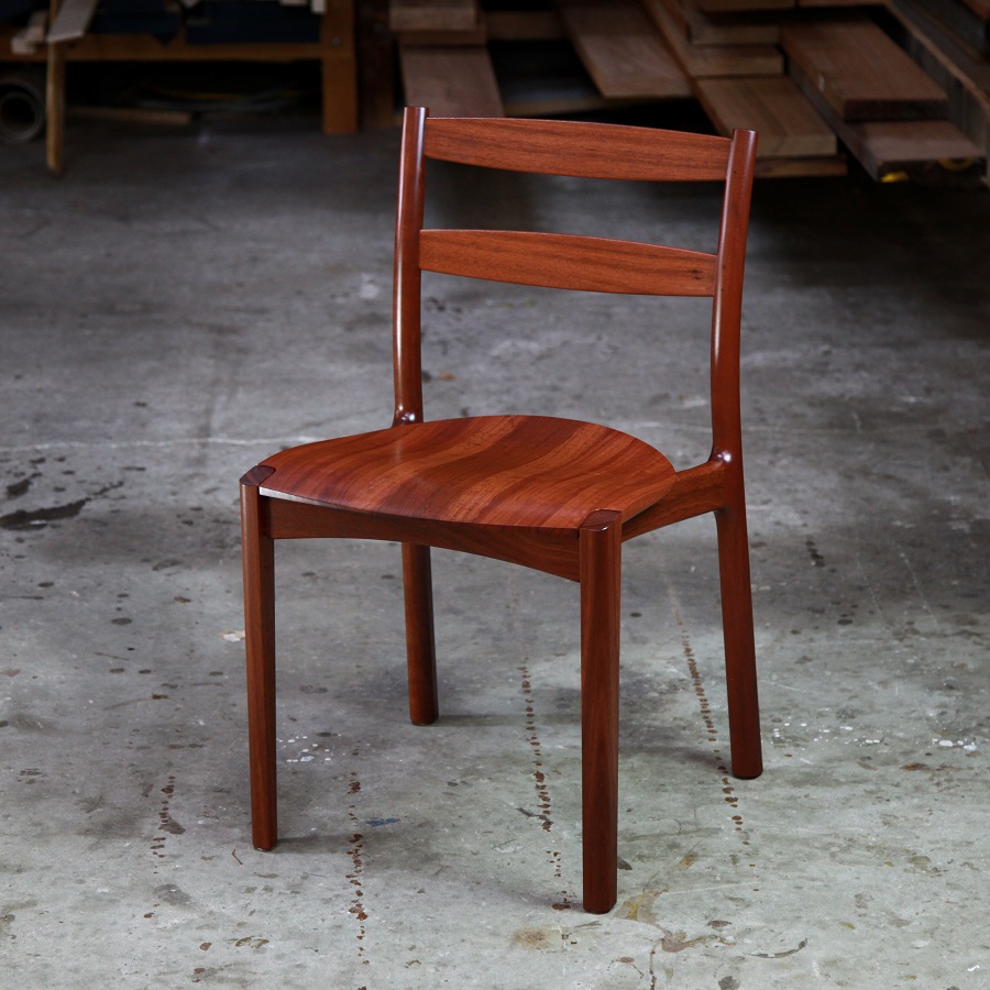 An Australian designed and made low back dining chair in jarrah in a woodworking workshop.