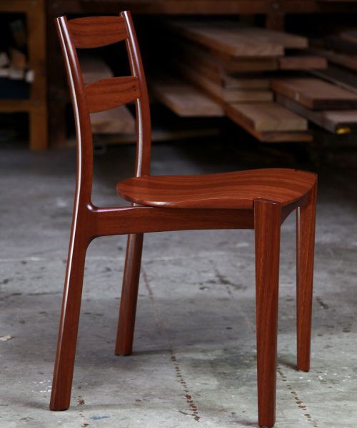 An Australian designed and made low back dining chair in jarrah in a woodworking workshop.