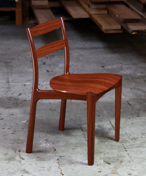 An Australian designed and made low back dining chair in jarrah in a woodworking workshop.