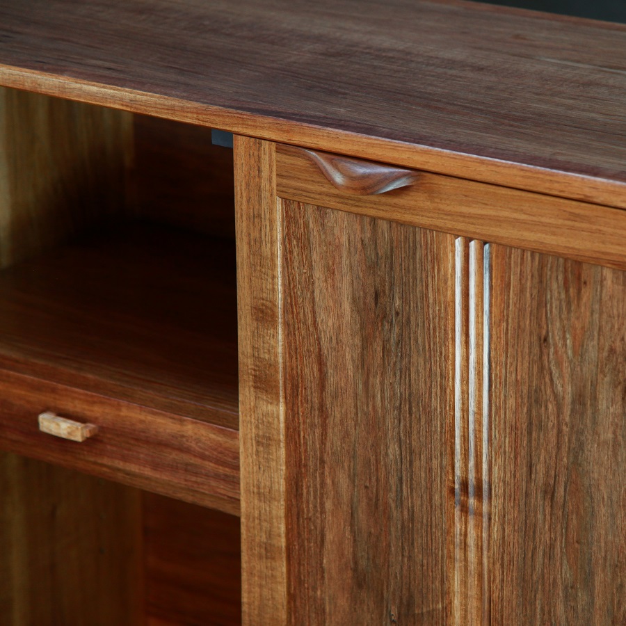 A photograph of a four door cabinet in a woodworking workshop with natural light highlighting the warm grain.