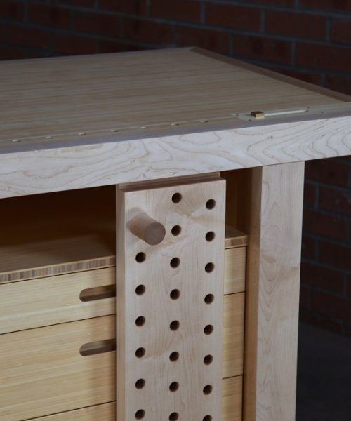 An HNT Gordon tail vice and a sliding deadman is perfectly fitted to a rock maple and bamboo workbench in a woodworking workshop.