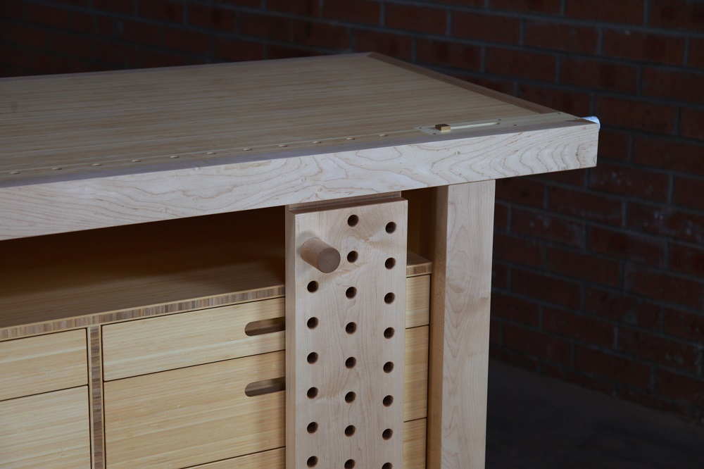 An HNT Gordon tail vice and a sliding deadman is perfectly fitted to a rock maple and bamboo workbench in a woodworking workshop.