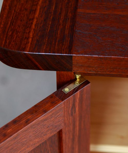 Door detail of a brass Brusso hinge fitted to beautiful jarrah cabinet.