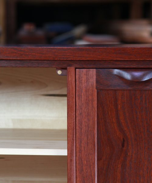 Door detail of a jarrah and rock maple cabinet featuring a hand made door pull.