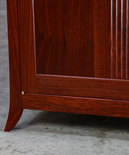 The foot detail of a beautiful jarrah cabinet with fluted doors.