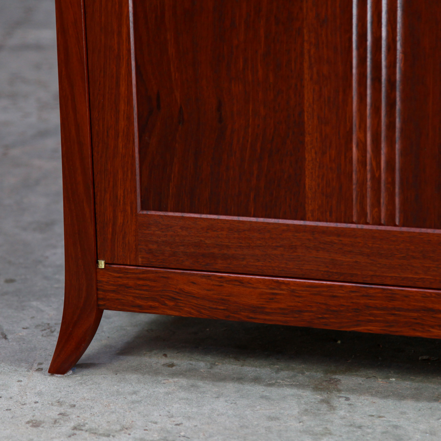The foot detail of a beautiful jarrah cabinet with fluted doors.