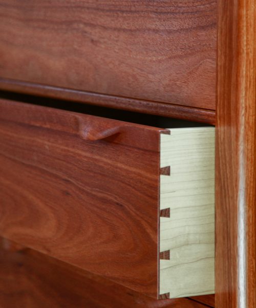 An open drawer in a fine jarrah and rock maple Lakeview 3 chest of drawers in front of a timber rack in a workshop.