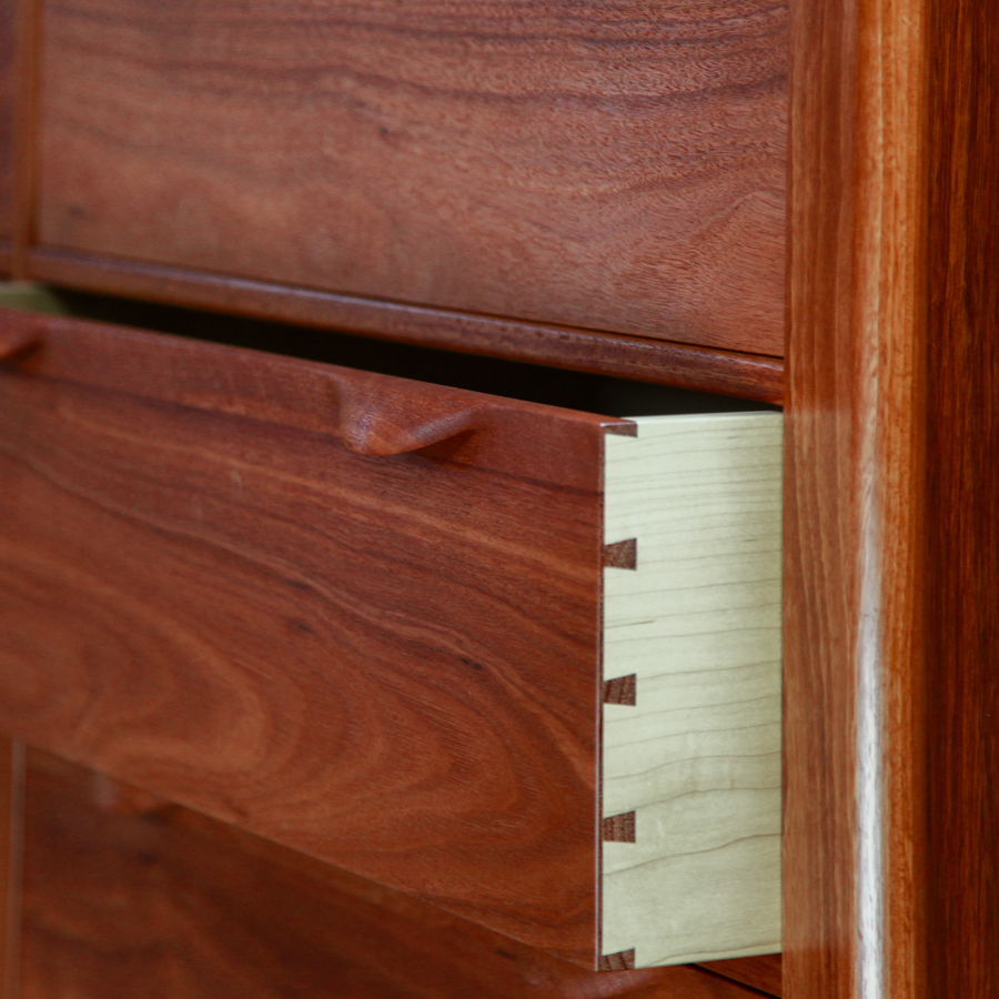 An open drawer in a fine jarrah and rock maple Lakeview 3 chest of drawers in front of a timber rack in a workshop.
