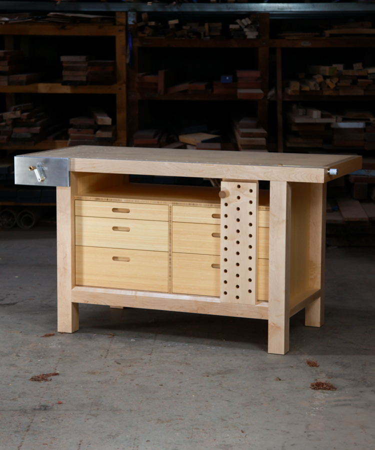 A beautiful woodworking bench sits in the workshop in front of a timber rack