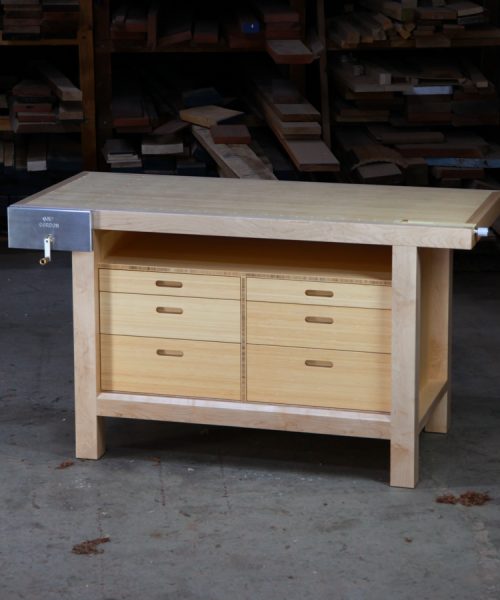 A beautiful woodworking bench sits in the workshop in front of a timber rack