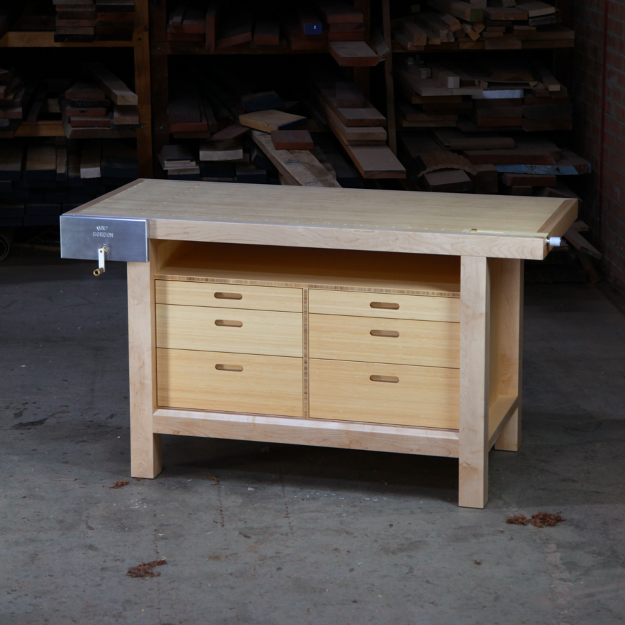 A beautiful woodworking bench sits in the workshop in front of a timber rack