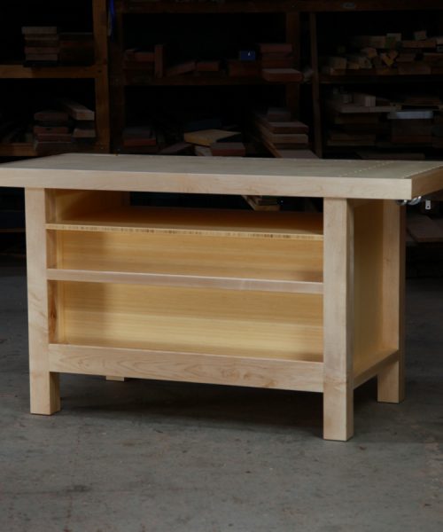 A beautiful woodworking bench sits in the workshop in front of a timber rack