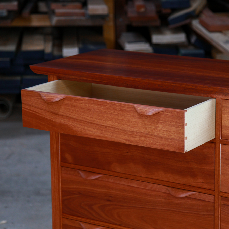 An open drawer in a fine jarrah and rock maple Lakeview 3 chest of drawers in front of a timber rack in a workshop.